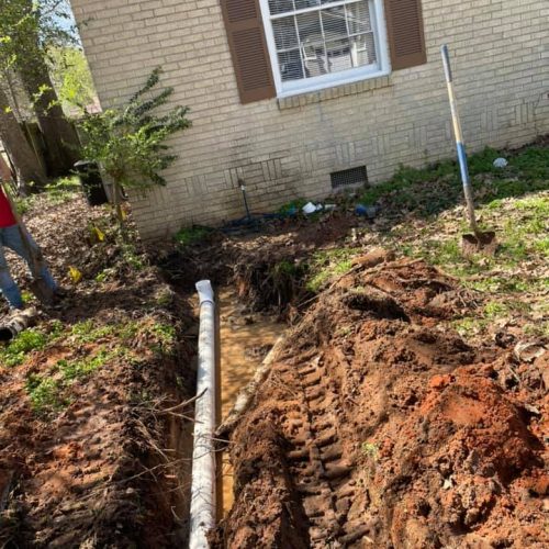 Residential sewer line replacement trench alongside home by SOS Plumbing.